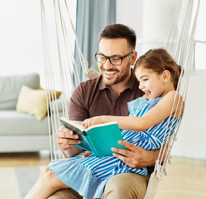 Father sitting with daughter on his knee reading a book